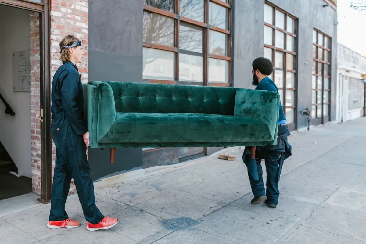 Crew carrying a sofa out of a building
